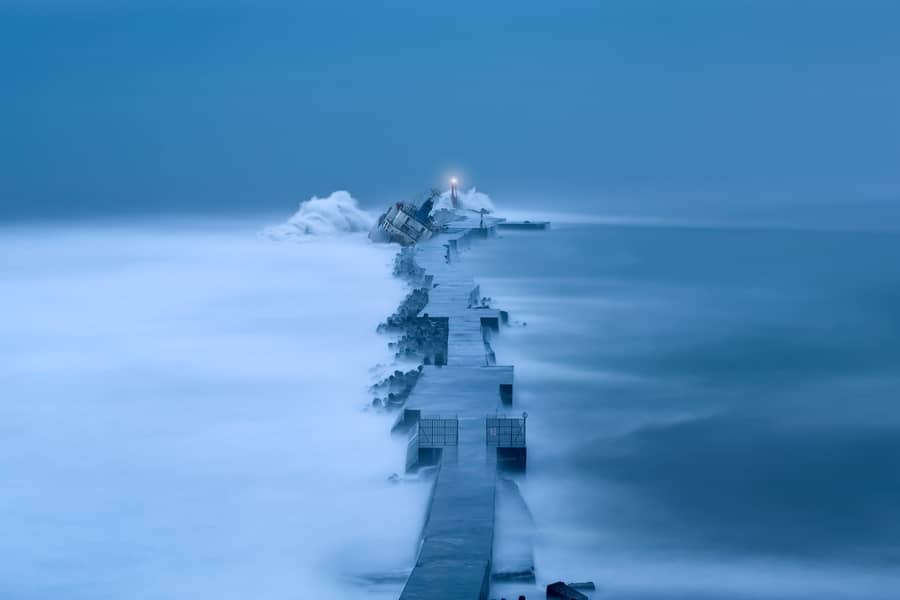 A ship tranded in the icy, blue weather in the distance. 