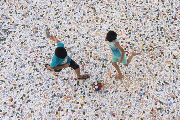 two boys playing football on a mosaic street floor