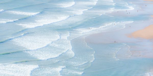 Aerial view of the ocean and waves with people swimming.