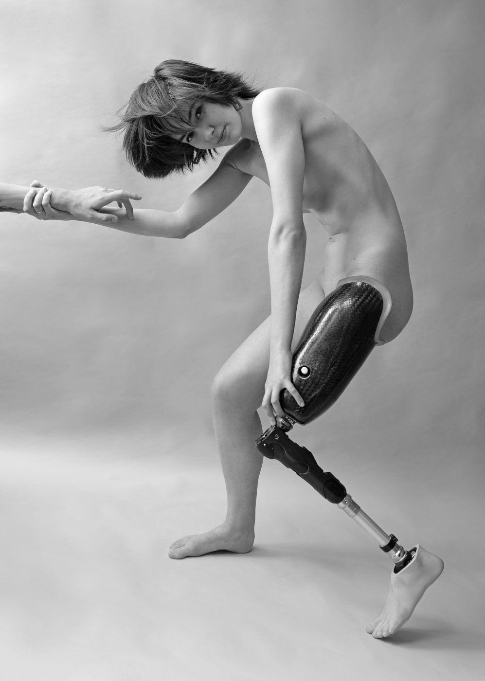 Black and white image of a naked woman with a prosthetic leg.